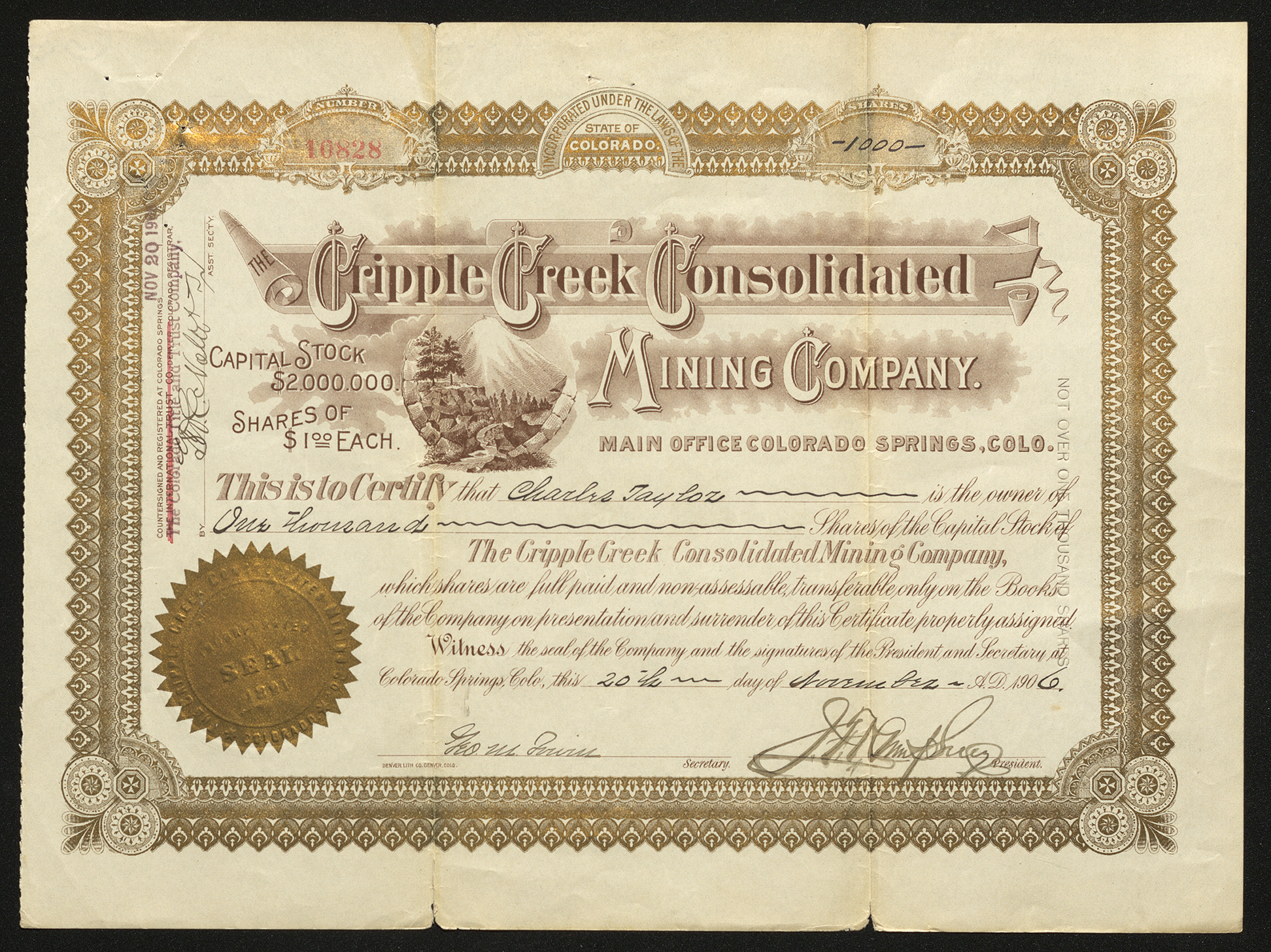 Certificate with brown and gold ink shows intricate bordering, lettering, a company seal, signatures, and a vignette of a mountain scene